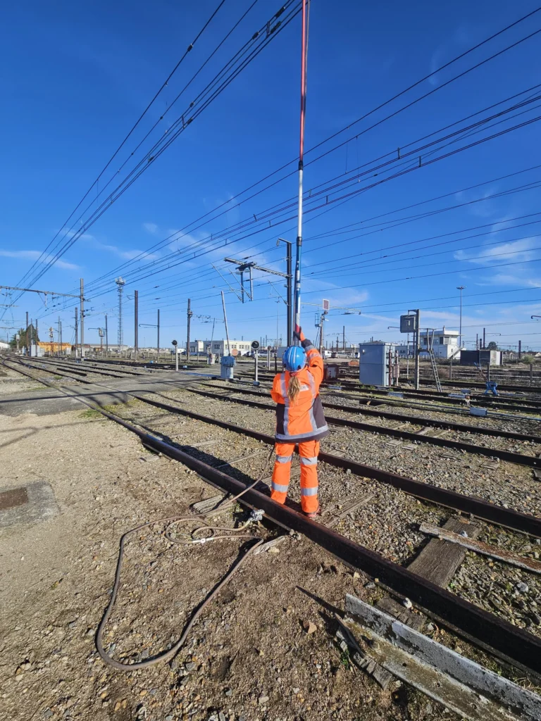 Formateur Rail compétences effectuant une vérification d'absence de tension (VAT) sur caténaire